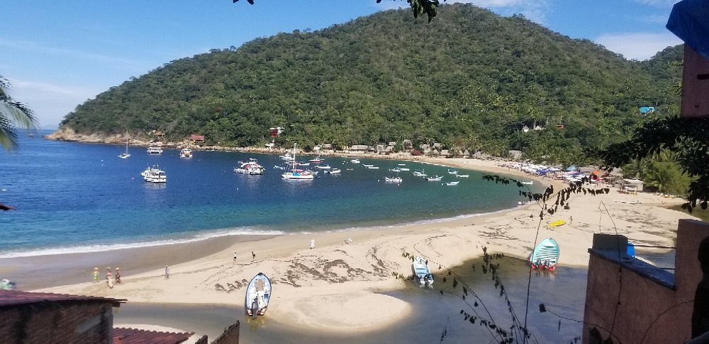 Aerial view of Yelapa Beach with boats docked and people snorkeling near the shore.