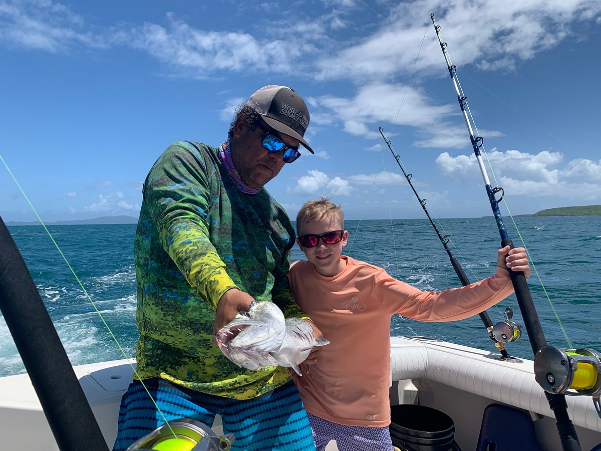 Father and son holding a fishing rod on a boat with a happy smile