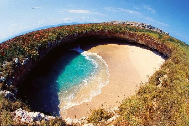 photo of a small private beach surrounded by cliffs and greenery.